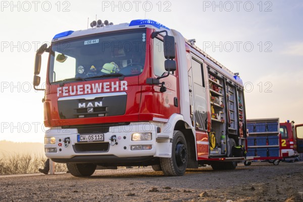 A fire engine with an open equipment door on a street in the morning light, ready to be deployed,
