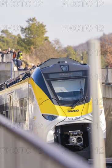 A train runs along the edge at an elevated point with spectators, fire department exercise at the