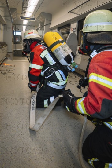 Two firefighters prepare a hose in the interior of a train, fire department exercise on the Hermann