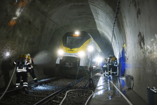 Firefighters during an emergency operation in a dark train tunnel next to a stationary train, fire
