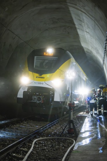 Train crosses an impressively illuminated tunnel with firefighters, fire brigade exercise on the