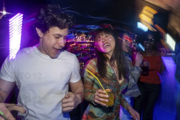 Young diverse people are dancing and interacting in a discotheque, surrounded by colorful neon