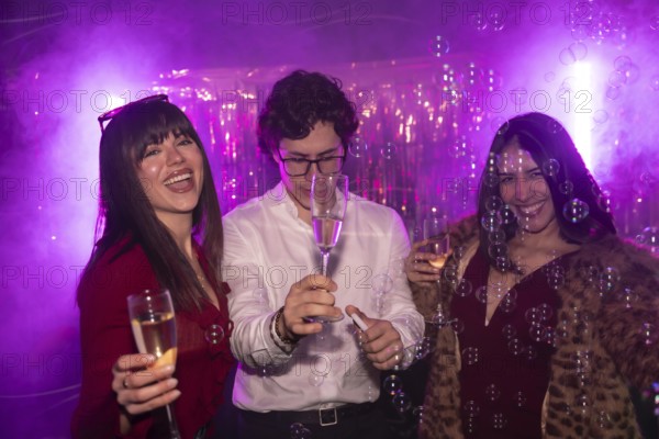 Friends cheering and having fun while celebrating a party with champagne and bubbles, experiencing