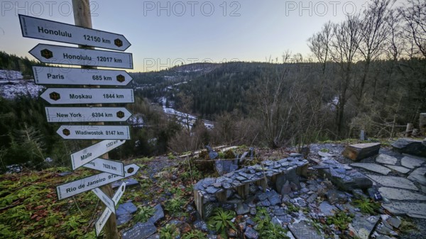 Wooden signpost at a viewpoint with views over wooded hills and valleys in winter, Franconian