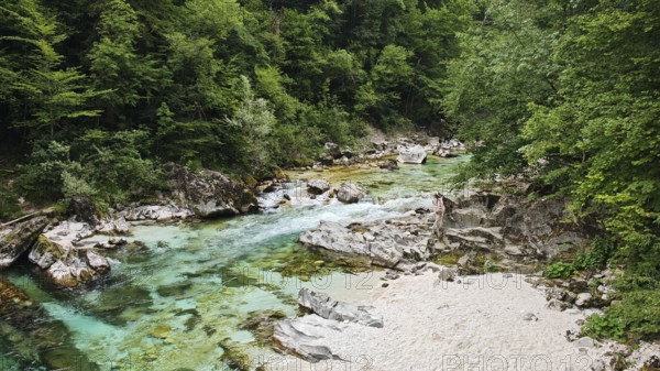 Clear river with rocks and green forest in the background, calming natural landscape, Soca valley,