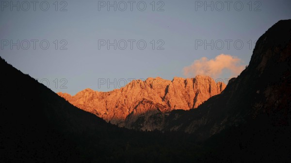 Mountains at sunset with golden rocks, alpine glow, and dark silhouettes in the foreground,