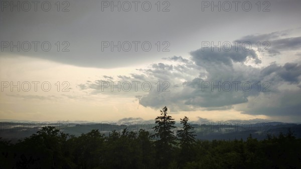 Massive clouds pile up over a green, wooded landscape, Fichtelgebirge
