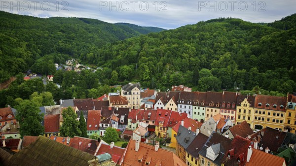 Panorama of a city with colorful roofs surrounded by wooded hills, view of Loket from above, Czech