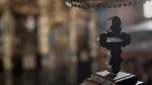 An intricately carved wooden cross against a blurred church background with mystical reflections,