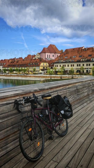Bicycle on a bridge across a river with historic buildings in the background under cloudy sky,