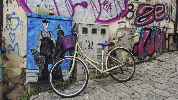 Vintage bicycle leaning against graffiti-decorated wall in urban setting, creative and lively