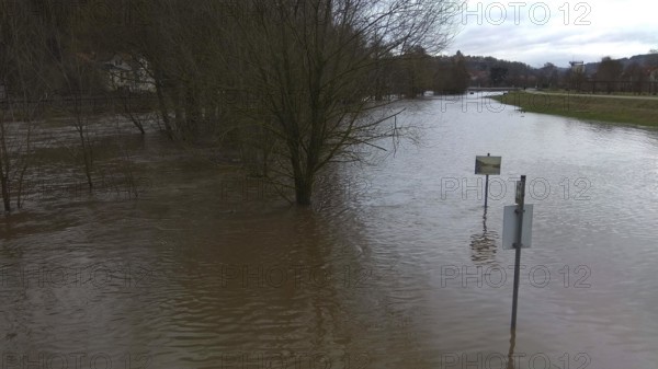 Flooded landscape with half-submerged trees and cloudy water, winter floods after snowmelt,