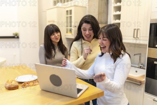 Group of female friends gathering in a modern kitchen, sharing an exciting moment while celebrating