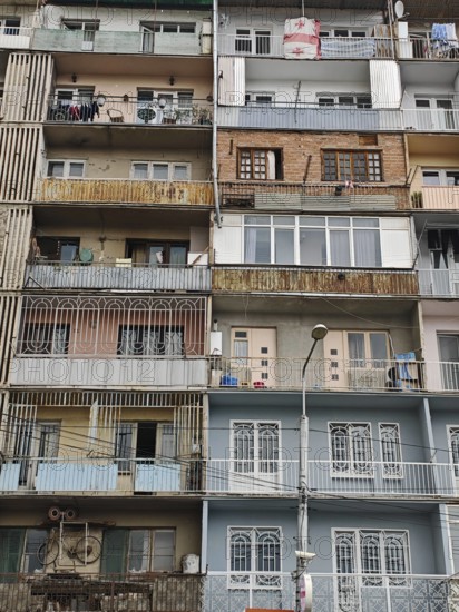 An urban high-rise building with various colorful balconies showing different areas of life,