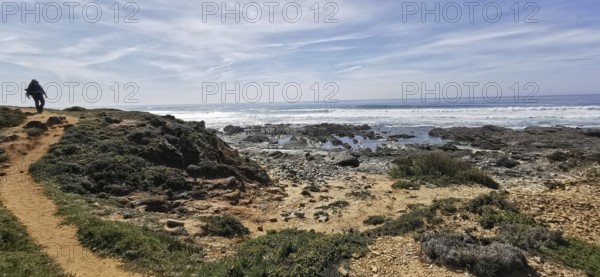 A hiker on a trail next to the rocky coast, Southwest Alentejo Natural Park and Vicentina Coast,