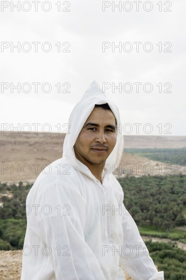 Young man and oasis in the background, near Merzouga, Meknès-Tafilalet region, Erg Chebbi, northern