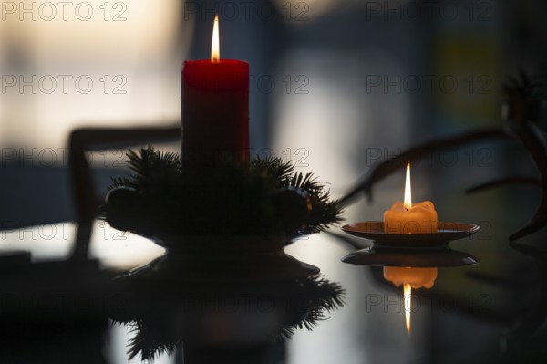 Two candles stand on a table in front of a window at dusk and create a Christmas atmosphere,
