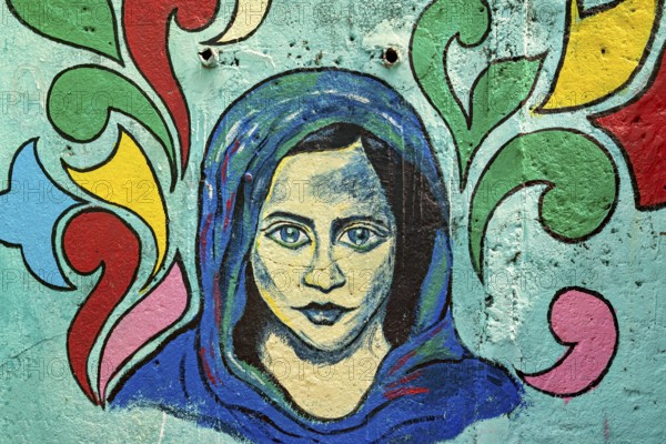 Colorful wall mural of a woman with a headscarf on a light blue background