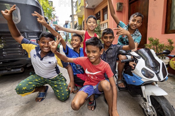 Children pose with a toy motorcycle on the street and are obviously having fun