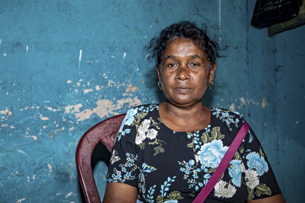 Portrait of a woman in front of a blue, peeling wall in an interior