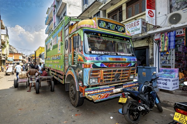 Colourful truck on a busy Indian street with shops and people in sunny weather, The colorful trucks