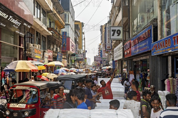 Close-traffic street market with people, rickshaws and colorful shop facades, the hustle and bustle