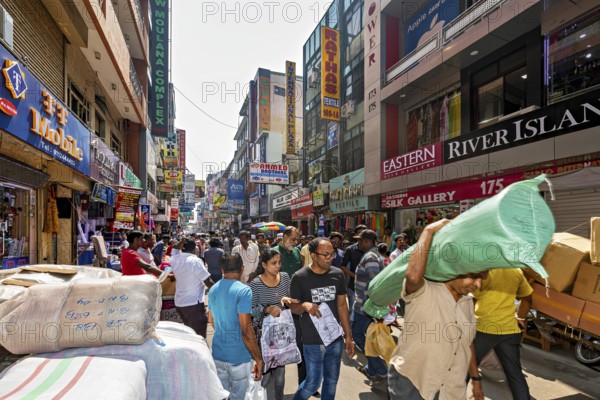 Well-visited shopping street with numerous people and payloads in bright sunlight, the hustle and