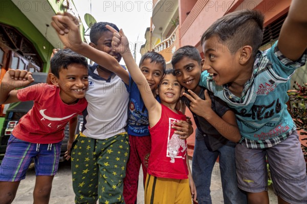 Six laughing and friendly children pose together on a street