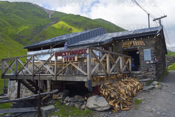 Guesthouse with wooden veranda in a mountain landscape under a cloudy sky, Cafe Svaneti, Ushguli,