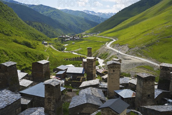 Village with several towers and a road in lush mountain scenery, defensive towers, Ushguli,