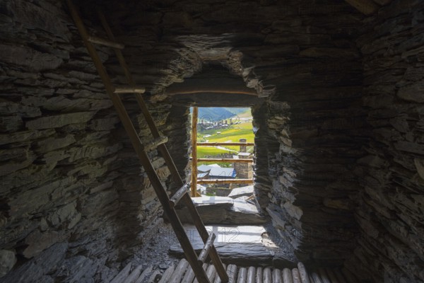 Stone interior of a defence tower with ladder and view of a green valley, in the tower of Queen