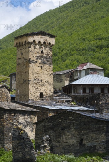 Historic stone building with a high tower in a green mountain valley, defensive towers, Ushguli,