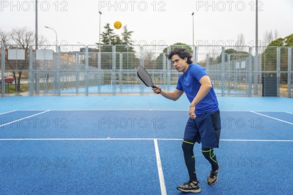 Athlete wearing athletic clothing using a paddle to hit a pickleball during an intense match,