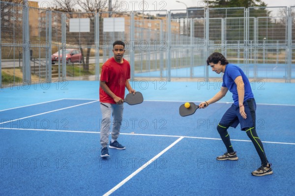 Two men intensely competing in pickleball on a vibrant blue outdoor court, focused and athletic as