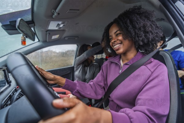 Smiling black woman driving with diverse friends, enjoying a carefree road trip, candid in car