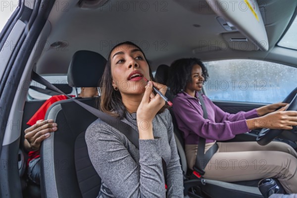 Women friends traveling together in a car, with a passenger applying lipstick using a makeup pencil