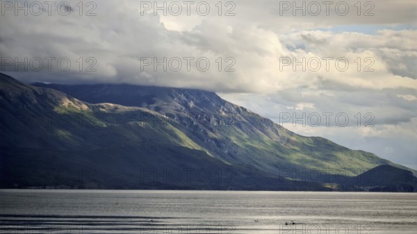 Dramatic mountain landscape with cloudy sky and calm lake in the foreground, Lake Ohrid, North