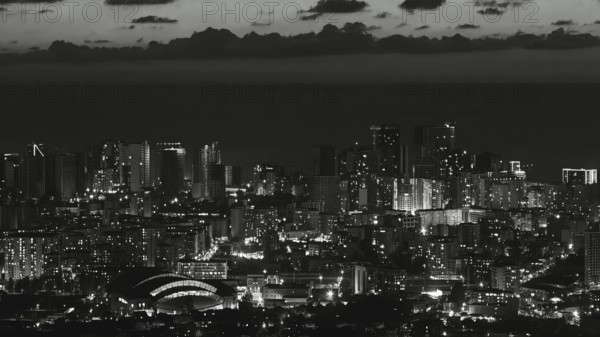 City view at night with illuminated skyscrapers and clouds in the sky in black and white, Batumi,