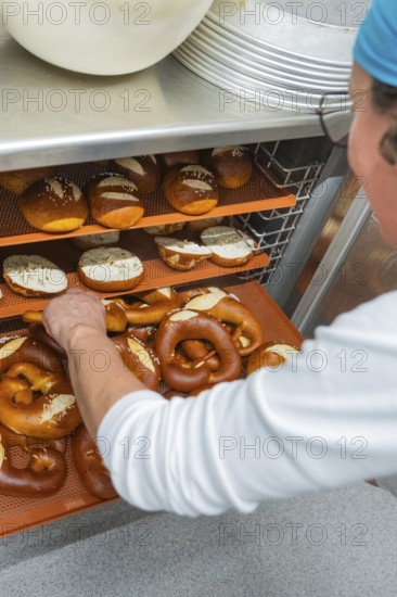 Baker places pretzels on shelves in a bakery, baking freshly baked goods, rolls, Haselstaller Hof,