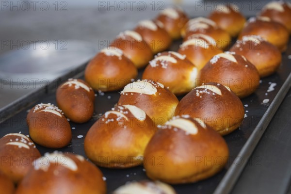 Several golden brown pretzel rolls with salt on a baking tray in the bakery, bake rolls,