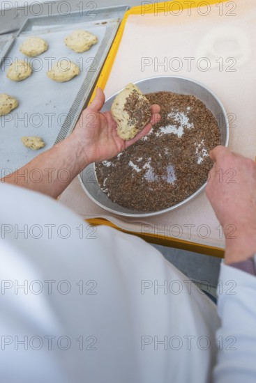A baker prepares dough by sprinkling it with linseeds, baking rolls, Haselstaller Hof, Gechingen,