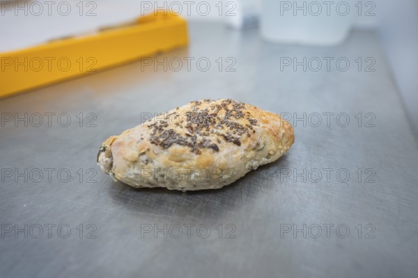 A roll with chia seeds is lying on a metal work surface in the bakery, bake rolls, Haselstaller