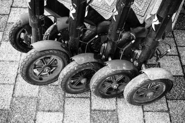 Black and white view of lined up, parked e-scooters on a paved surface, Singen am Hohentwiel,