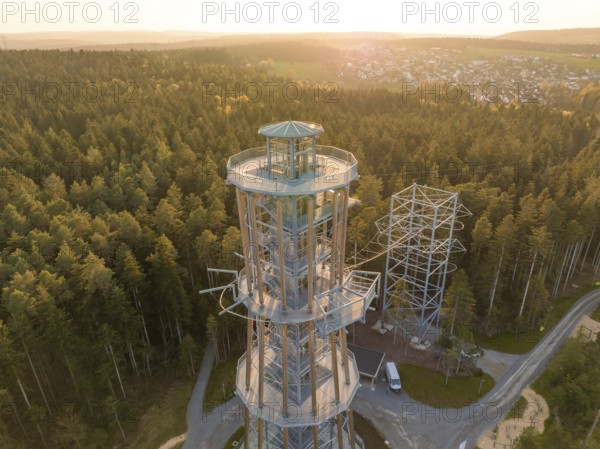 A high observation tower in the forest, surrounded by trails and illuminated by evening light,