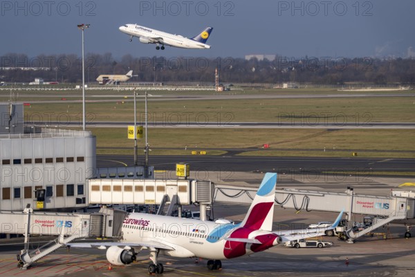 Düsseldorf airport, DUS, terminal A Eurowings aircraft at the gate, Lufthansa Airbus taking off