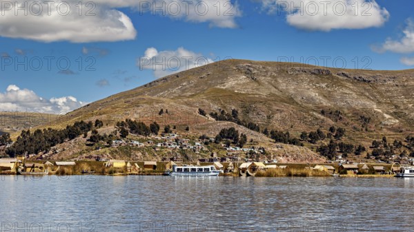 View of a lakeside village with hills in the background and clouds in the sky, The floating reed