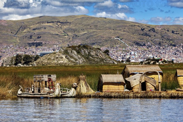 Reed houses and traditional lakeside boat under a cloudy sky with mountains, The floating reed