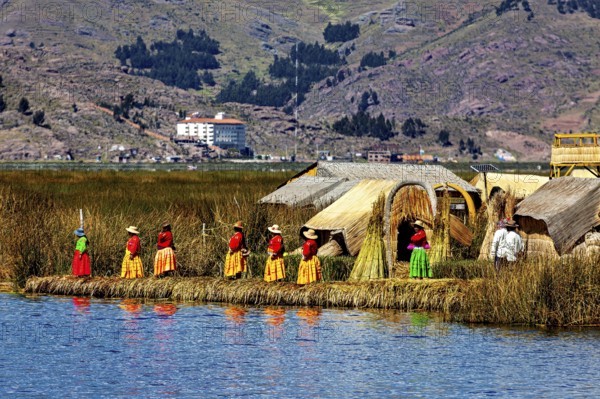 Women in traditional clothing in front of reed huts on an island in the lake, The floating reed