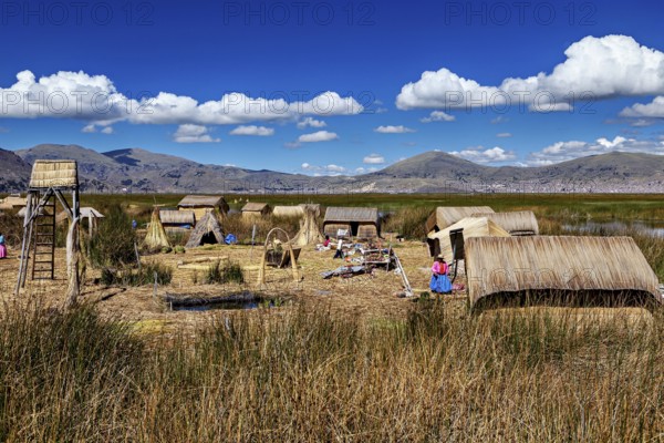 Reed village surrounded by mountains and under a clear blue sky, The floating reed islands of Uros