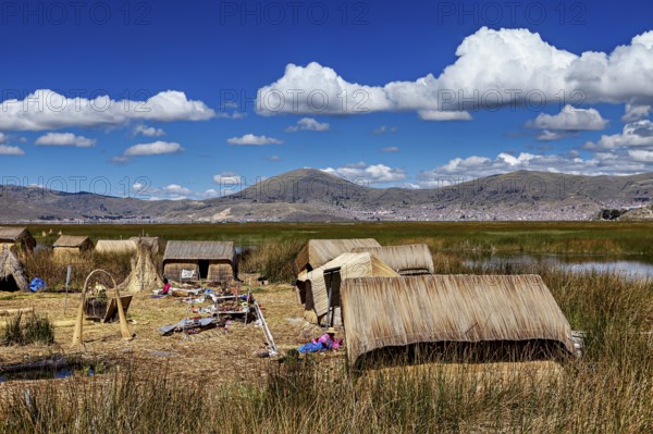 A village with reed huts on a lake under a cloudy blue sky, The floating reed islands of the Uros